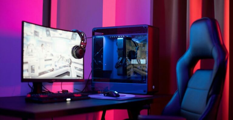 Chambre gaming avec un ordinateur, une chaise et un écran éclairée par des néons